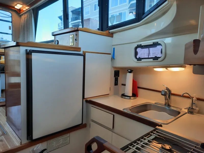 Slide: The Image of 2004 Camano Troll boat kitchen with sink, stove, and refrigerator. - 23