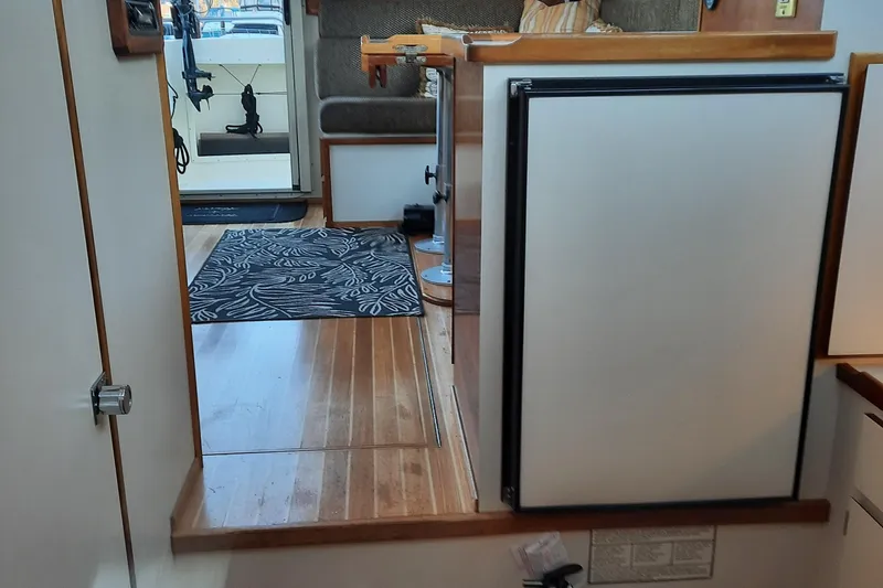 Slide: The Image of Interior of a 2004 Camano Troll boat, featuring wooden flooring and compact design. - 24