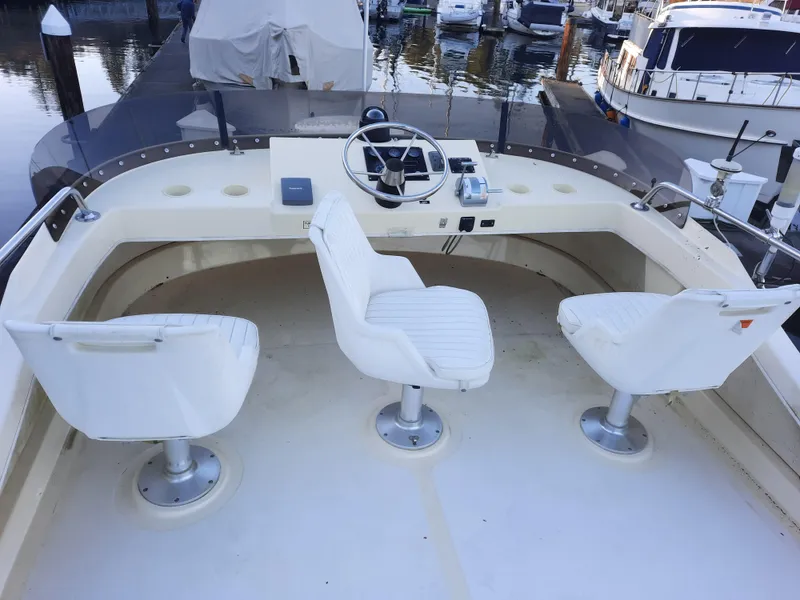 Slide: The Image of 2004 Camano Troll boat helm with three white swivel chairs in a marina setting. - 9