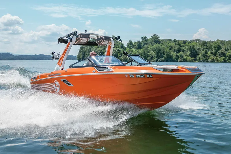 The Image of 2022 Centurion Ri245 boat cruising on a lake with lush green shoreline. - 0