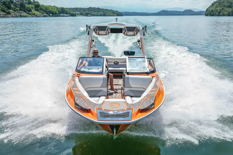 Slide: The Image of 2022 Centurion Ri245 boat cruising on a scenic lake with lush green hills. - 12