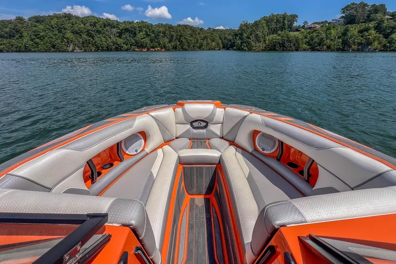Slide: The Image of 2022 Centurion Ri245 boat interior with orange and gray seating on a serene lake. - 15