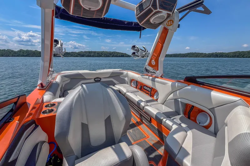 Slide: The Image of 2022 Centurion Ri245 boat interior with orange and gray seating on a lake. - 19