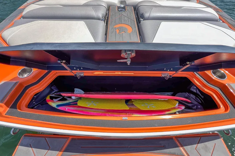 Slide: The Image of 2022 Centurion Ri245 boat with open storage compartment holding colorful surfboards. - 35