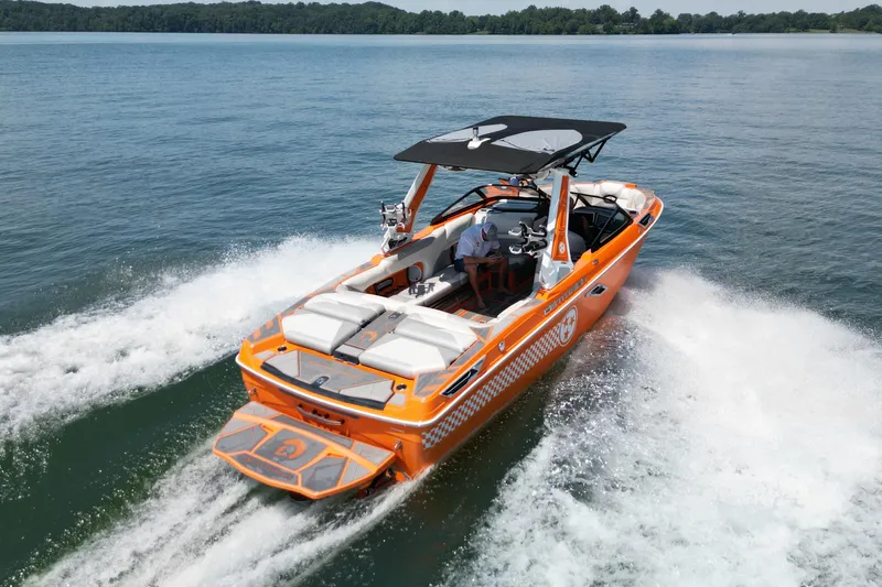 Slide: The Image of 2022 Centurion Ri245 boat cruising on a lake, vibrant orange design, creating waves. - 9