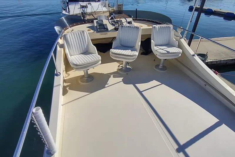 Slide: The Image of 2000 Camano Troll boat deck with three white swivel chairs, docked at marina. - 13