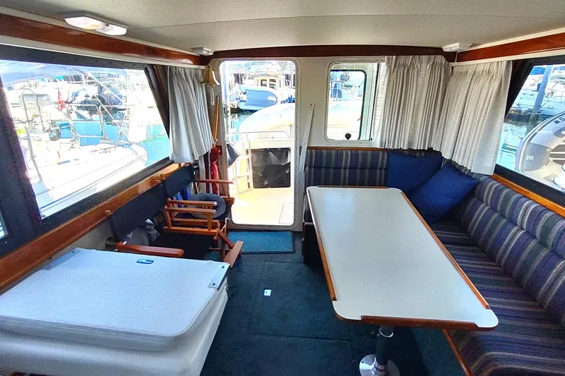 Slide: The Image of Interior of 2000 Camano Troll boat with seating, table, and windows overlooking marina. - 25