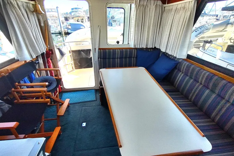 Slide: The Image of Interior of 2000 Camano Troll boat with striped seating and table, dock view. - 26