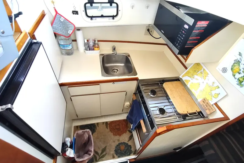 Slide: The Image of Compact kitchen in a 2000 Camano Troll boat with stove, sink, and map. - 36