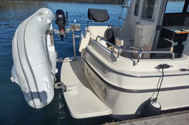 Slide: The Image of 2000 Camano Troll boat with dinghy attached, docked on calm water. - 4