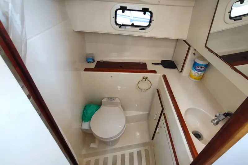 Slide: The Image of Compact bathroom in a 2000 Camano Troll boat, featuring toilet, sink, and storage. - 42
