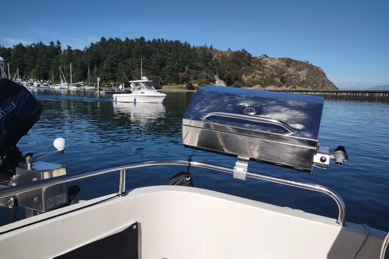 Slide: The Image of Camano Troll 2000 boat with grill, docked near scenic shoreline and other boats. - 9