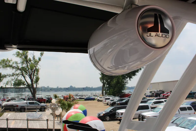 Slide: The Image of 2024 Cobalt R6 Surf boat with JL Audio speaker, lakeside view. - 12