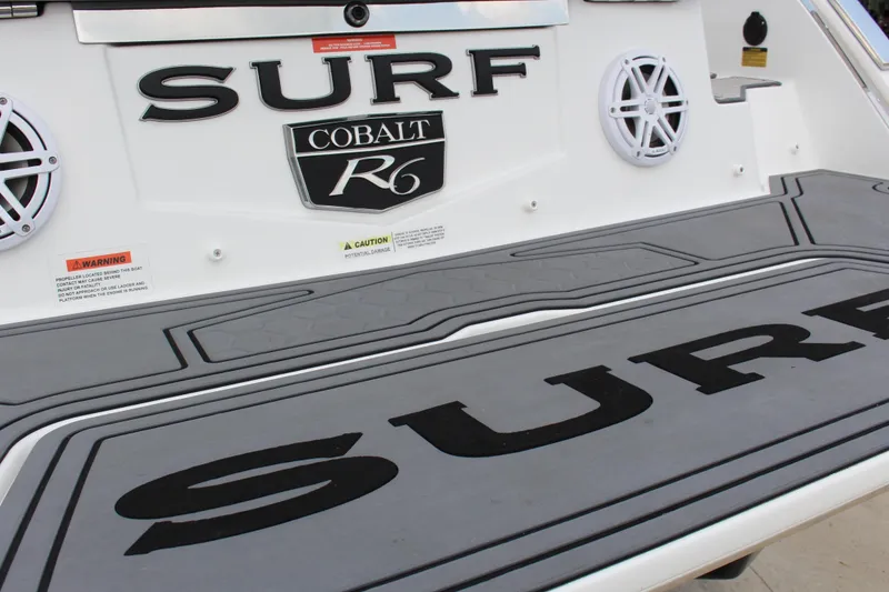 Slide: The Image of 2024 Cobalt R6 Surf boat deck with logo and warning labels. - 15
