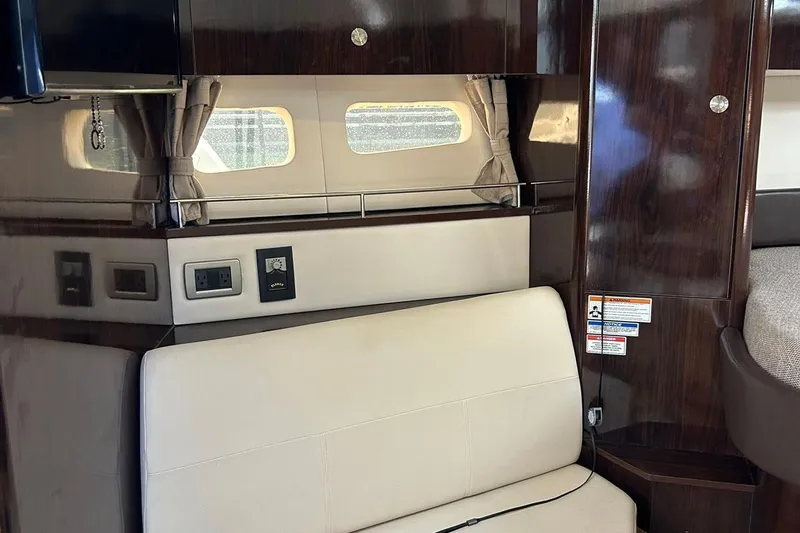 Slide: The Image of 2019 Sea Ray Sundancer 350 Coupe interior with beige seating and dark wood accents. - 12