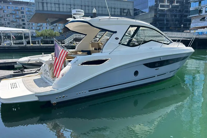 Slide: The Image of 2019 Sea Ray Sundancer 350 Coupe docked in a marina, displaying an American flag. - 2