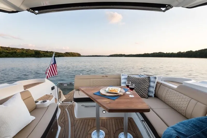 Slide: The Image of Manufacturer Provided Image: 2019 Sea Ray Sundancer 350 Coupe interior with dining setup on a serene lake. - 24
