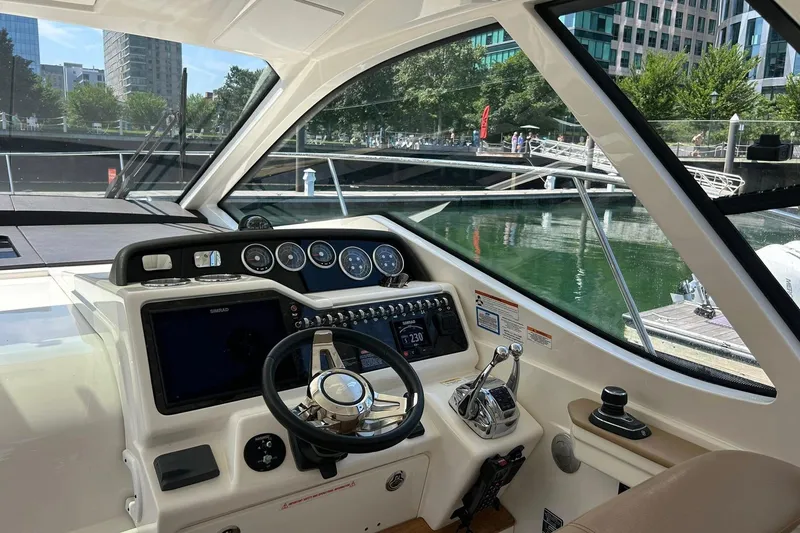 Slide: The Image of 2019 Sea Ray Sundancer 350 Coupe helm with modern controls and waterfront view. - 7