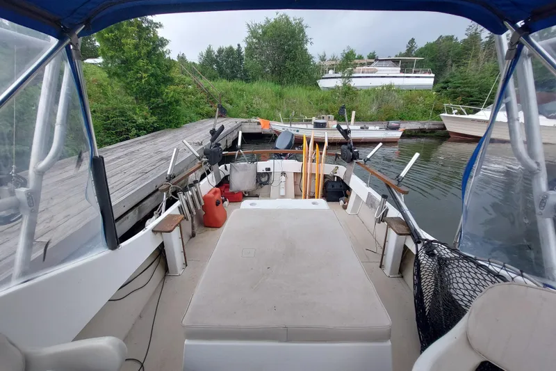 Slide: The Image of 1986 Shamrock 20 Walk Through boat docked, featuring open deck and fishing gear. - 4