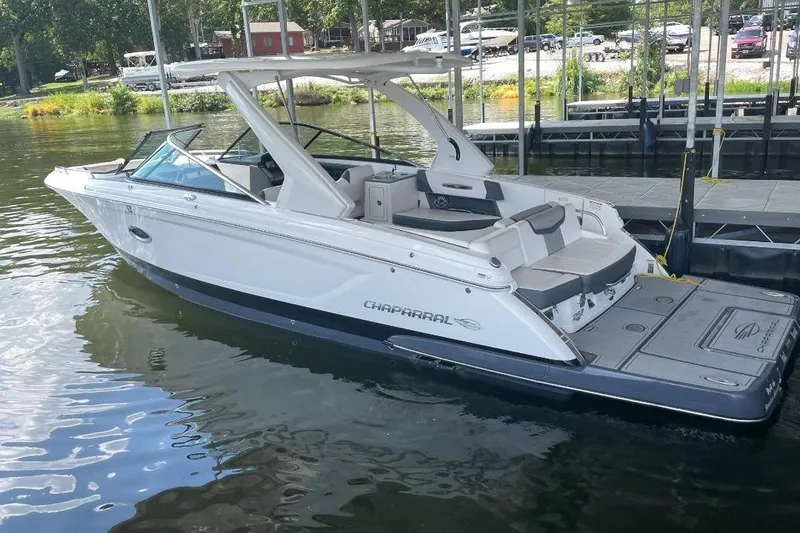 Slide: The Image of 2020 Chaparral 297 SSX boat docked on a calm lake, showcasing sleek design and spacious seating. - 2