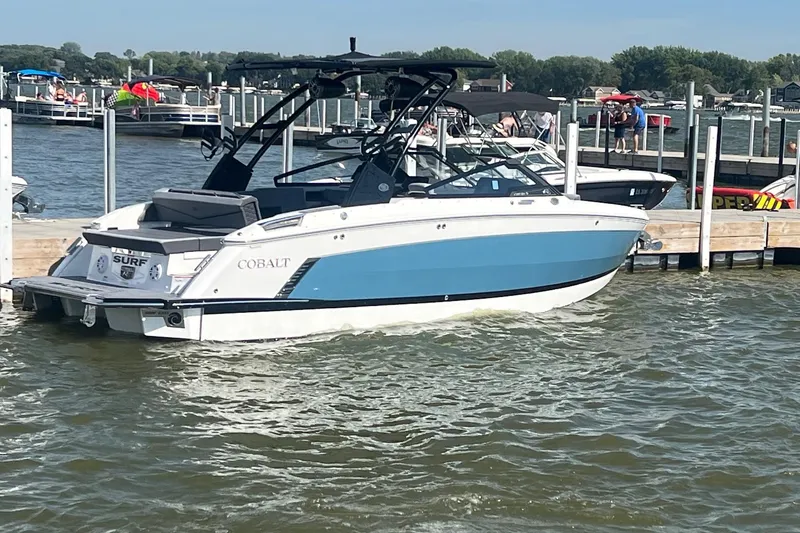 The Image of 2024 Cobalt R6 Surf boat docked on a sunny day at a busy marina. - 1