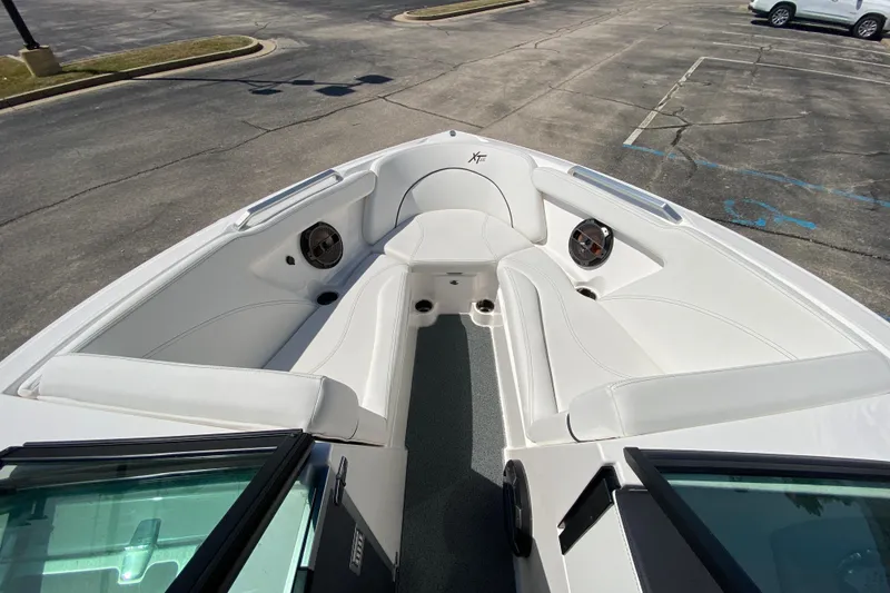 Slide: The Image of 2022 MasterCraft XT25 boat interior with white seating and speakers in a parking lot. - 32