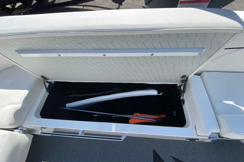 Slide: The Image of 2022 MasterCraft XT25 boat storage compartment with open lid, revealing interior space and equipment. - 38