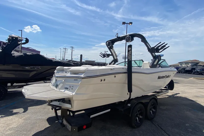 Slide: The Image of 2022 MasterCraft XT25 boat on trailer under clear blue sky. - 4