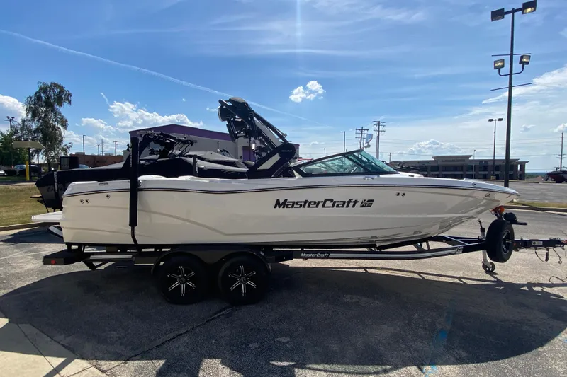 Slide: The Image of 2022 MasterCraft XT25 boat on trailer under clear sky. - 5