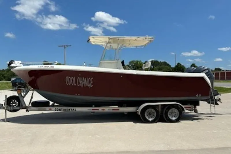 Slide: The Image of 2006 Sailfish 2660 CC boat on trailer, parked on grass under clear blue sky. - 3