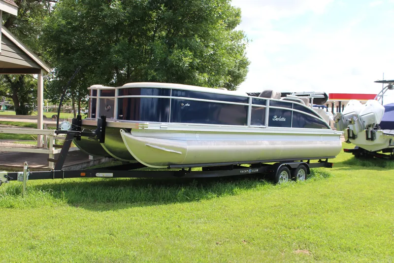 The Image of 2024 Barletta Aria 24UC pontoon boat on trailer, parked on grass. - 1