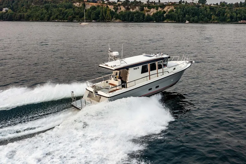 Slide: The Image of 2019 Targa 35 boat cruising on a scenic lake with lush green shoreline. - 2