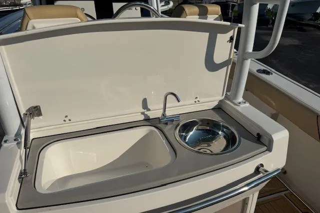 Slide: The Image of 2025 Drakkar 280CC boat sink and faucet setup with beige seating in background. - 11