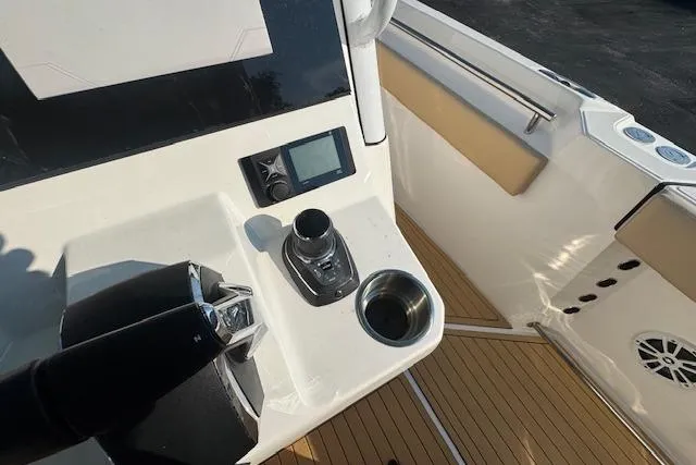 Slide: The Image of 2025 Drakkar 280CC boat cockpit with control panel, joystick, and cup holder on teak flooring. - 17