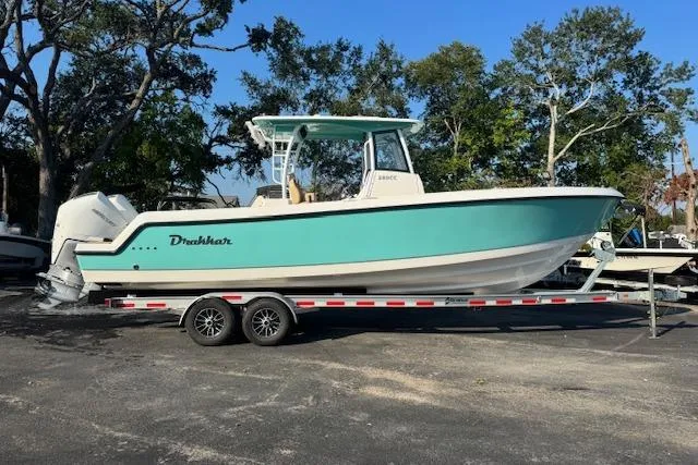 Slide: The Image of 2025 Drakkar 280CC boat on trailer, turquoise hull, parked outdoors. - 2