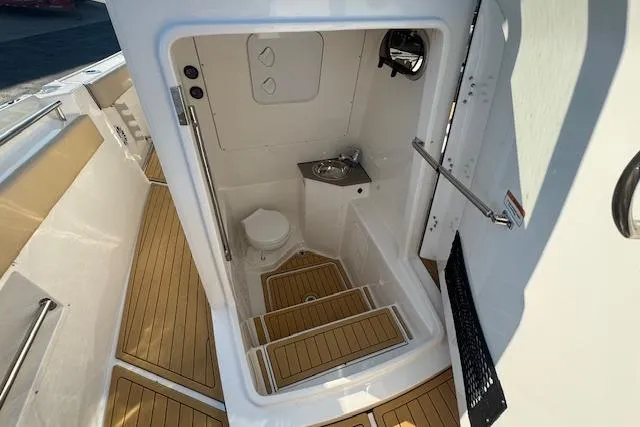 Slide: The Image of Interior of 2025 Drakkar 280CC boat featuring compact bathroom with toilet and sink. - 22
