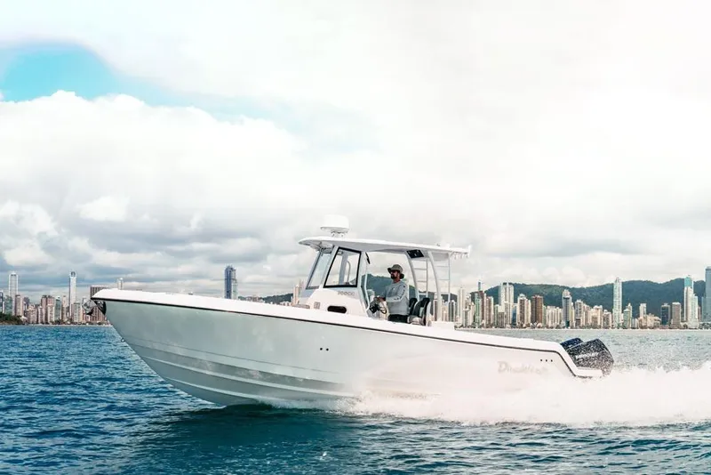 Slide: The Image of 2025 Drakkar 280CC boat cruising on water with city skyline in background. - 25