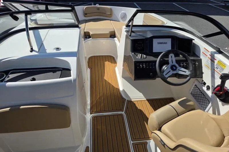 Slide: The Image of 2025 Bayliner VR6 OB boat interior with tan seating and wood-style flooring. - 4