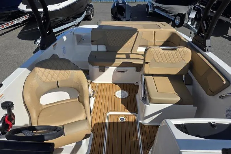 Slide: The Image of 2025 Bayliner VR6 OB boat interior with tan seating and wood flooring. - 5