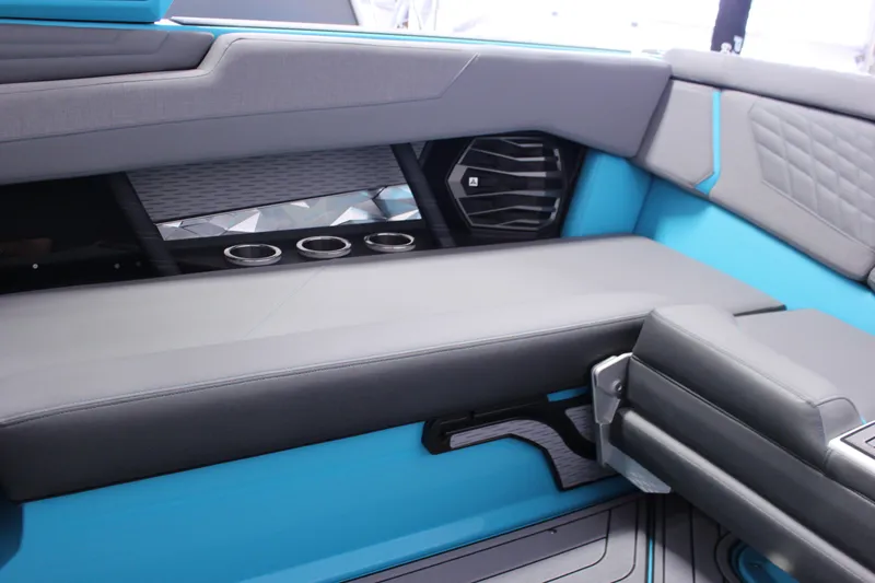 Slide: The Image of 2023 Nautique G25 interior with gray and blue seating, cup holders, and speaker. - 11