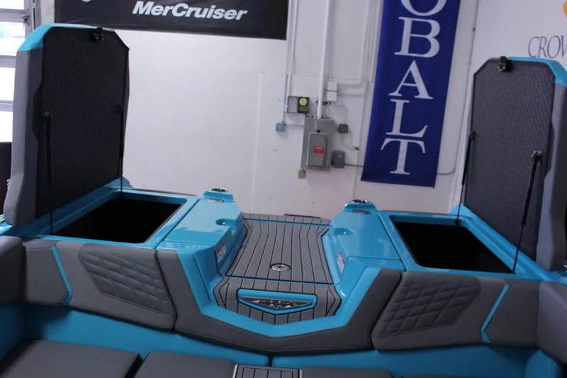 Slide: The Image of 2023 Nautique G25 boat interior with open storage compartments, featuring blue and gray upholstery. - 13