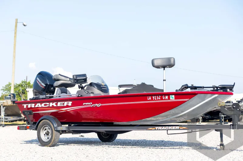 Slide: The Image of 2022 Tracker Pro 170 boat in red, parked on a trailer in a gravel lot. - 3