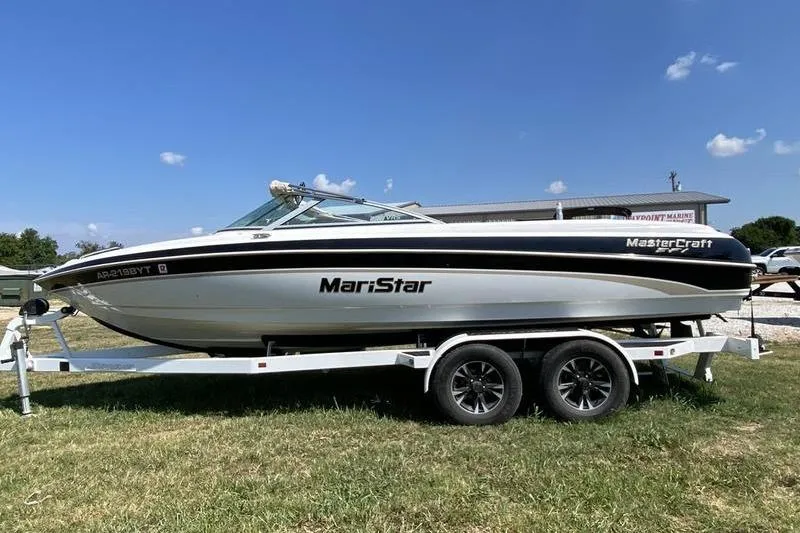 Slide: The Image of 2001 MasterCraft MariStar 230 VRS boat on trailer, parked on grass under clear blue sky. - 1