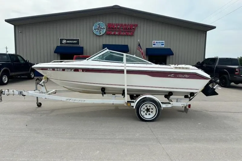 The Image of 1989 Sea Ray 160 Bow Rider on trailer outside a marine dealership. - 1