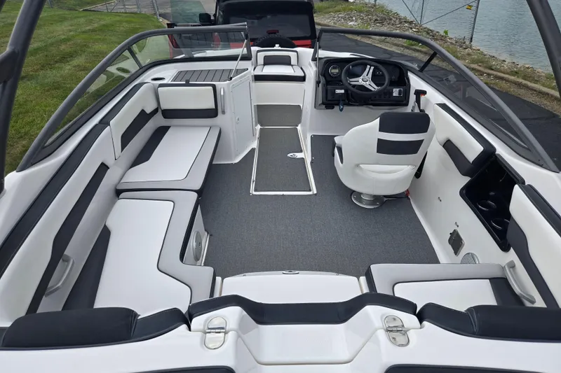 Slide: The Image of 2019 Yamaha Boats AR195 interior with seating and steering wheel, docked by a lake. - 11