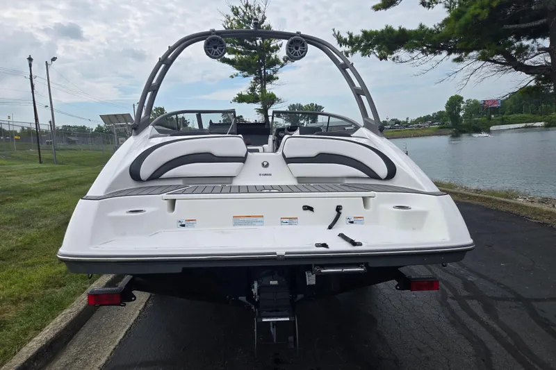 Slide: The Image of 2019 Yamaha Boats AR195, rear view by a lakeside, showcasing sleek design and seating. - 2