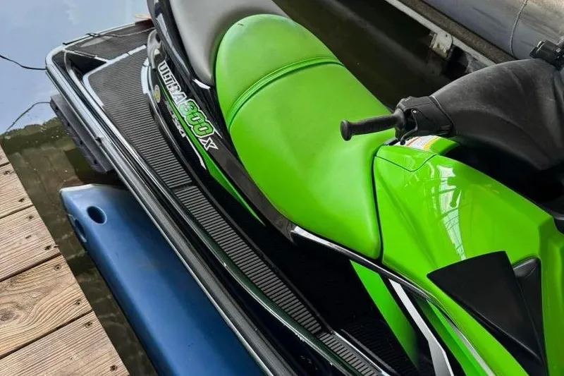 Slide: The Image of 2011 Kawasaki Ultra 300 X Jet Ski with vibrant green seat docked by water. - 2
