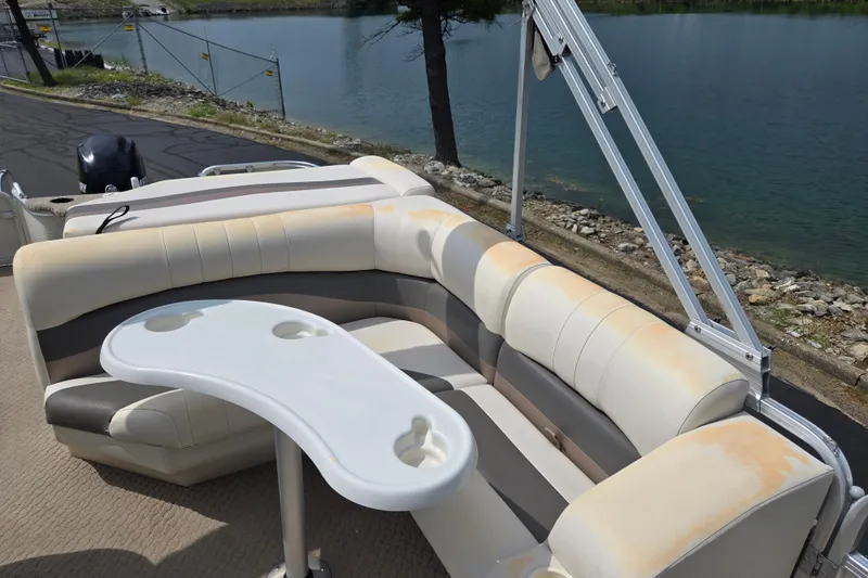 Slide: The Image of 2007 Suncruiser Trinidad 204 pontoon boat with seating and table by a lakeside. - 16