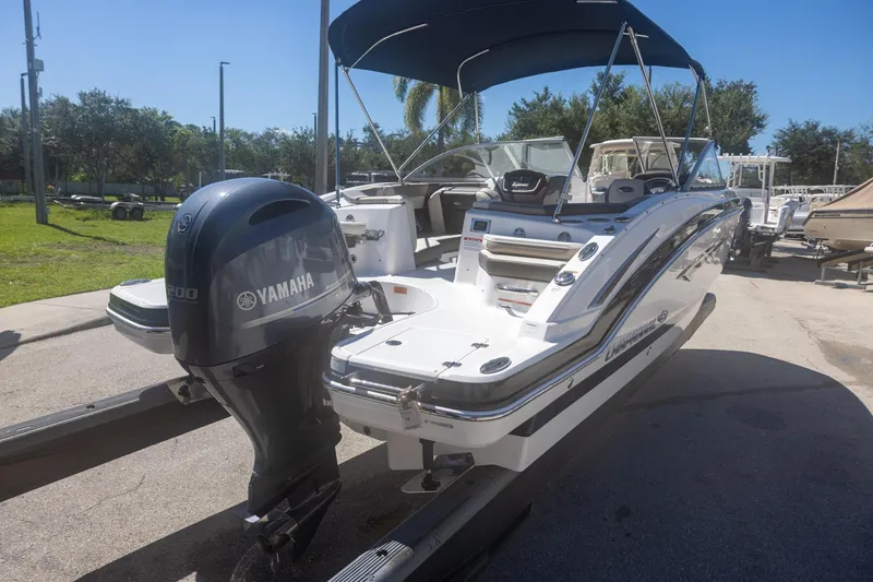 Slide: The Image of 2019 Chaparral 230 Suncoast boat with Yamaha engine, parked outdoors under blue sky. - 4