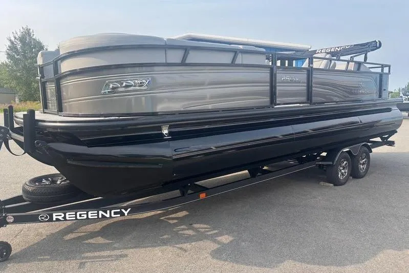 Slide: The Image of 2025 Regency 250 DL3 pontoon boat on trailer, sleek design, parked outdoors. - 9
